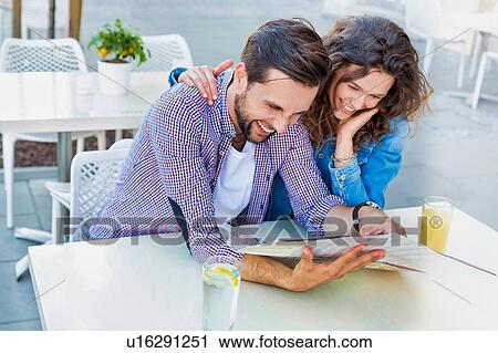 Young attractive couple smiling while looking at the menu in restaurant View Large Photo Image Stock Image - Young attractive couple smiling while looking at the menu in restaurant. Fotosearch