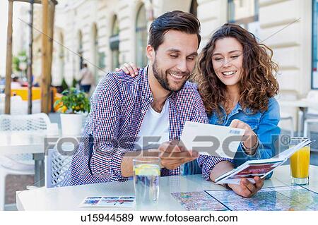 Stock Photo - Young attractive couple smiling while looking at the menu in restaurant. Fotosearch