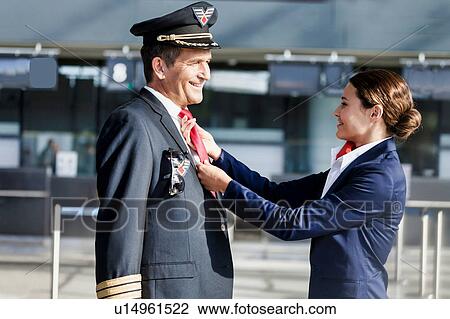 Young attractive flight attendant adjusting pilot neck tie in airport View Large Photo Image Stock Image - Young attractive flight attendant adjusting pilot neck tie in airport. Fotosearch