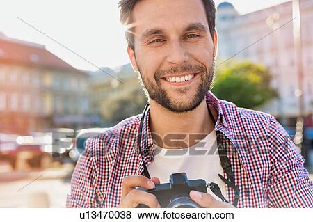 Young attractive man holding camera and taking photo View Large Photo Image Stock Photo - Young attractive man holding camera and taking photo . Fotosearch