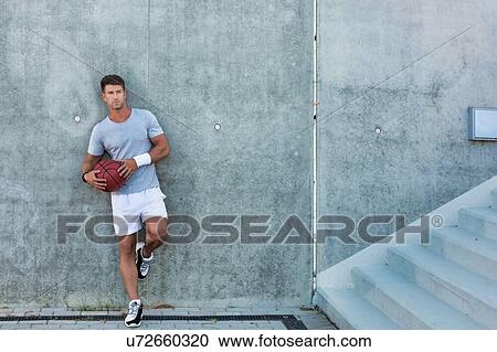 Young attractive man leaning on wall while holding ball View Large Photo Image Stock Image - Young attractive man leaning on wall while holding ball. Fotosearch