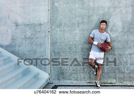 Young attractive man leaning on wall while holding ball View Large Photo Image Stock Image - Young attractive man leaning on wall while holding ball. Fotosearch