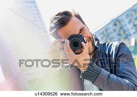 Stock Photograph - Young attractive man photographing the beautiful views in the city. Fotosearch