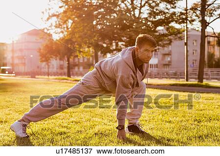 Stock Photo - Young attractive man stretching in park. Fotosearch