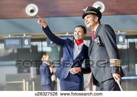 Young attractive stewardess pointing aircraft with the pilot in airport View Large Photo Image Stock Photo - Young attractive stewardess pointing aircraft with the pilot in airport. Fotosearch