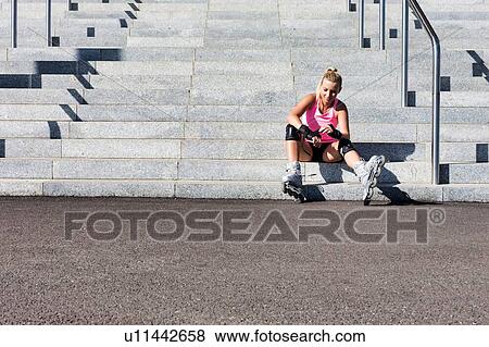 Young attractive woman adjusting safety gear while wearing rollerblades View Large Photo Image Stock Photo - Young attractive woman adjusting safety gear while wearing rollerblades. Fotosearch