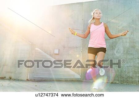 Picture - Young attractive woman exercising by jumping on rope . Fotosearch