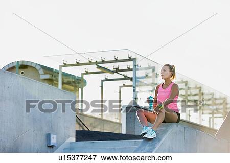 Stock Photo - Young attractive woman sitting while drinking energy drink . Fotosearch