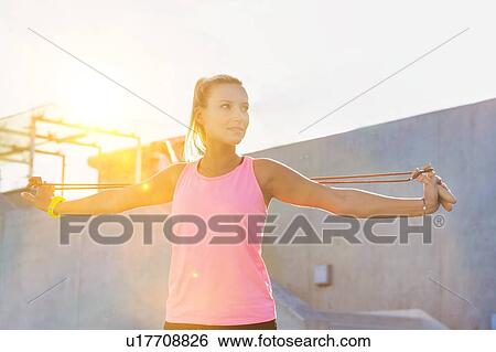 Stock Photograph - Young attractive woman stretching her arms with rope . Fotosearch