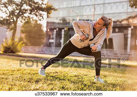 Stock Photo - Young attractive woman stretching in park. Fotosearch