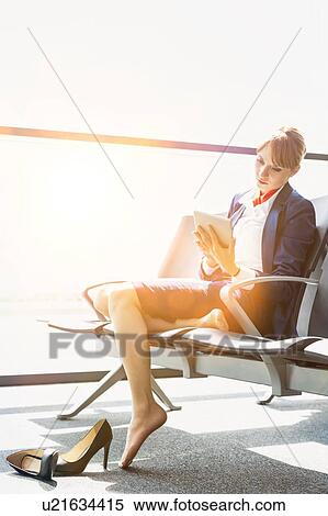 Young beautiful airport staff using digital tablet while sitting on chair during break View Large Photo Image Stock Photography - Young beautiful airport staff using digital tablet while sitting on chair during break . Fotosearch