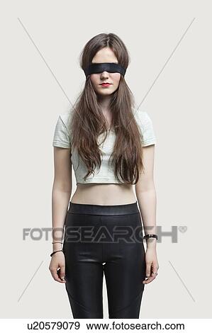Young blindfolded woman standing against gray background View Large Photo Image Stock Photo - Young blindfolded woman standing against gray background. Fotosearch