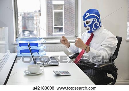 Young businessman celebrating victory in wrestling mask at office desk View Large Photo Image Stock Photo - Young businessman celebrating victory in wrestling mask at office desk. Fotosearch