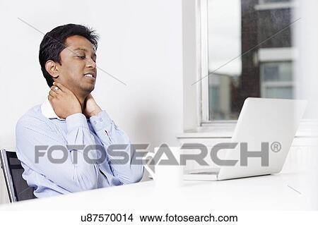 Picture - Young businessman looking at laptop in office. Fotosearch
