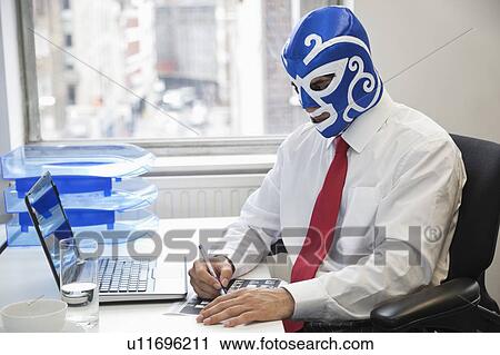 Young businessman working in office with wrestling mask on face at office desk View Large Photo Image Stock Image - Young businessman working in office with wrestling mask on face at office desk. Fotosearch
