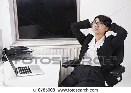 Young businesswoman resting on chair in front of laptop in office View Large Photo Image Stock Photo - Young businesswoman resting on chair in front of laptop in office. Fotosearch