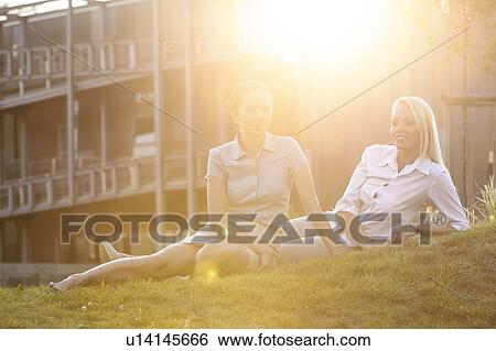 Stock Photograph - Young businesswomen relaxing on office lawn. Fotosearch