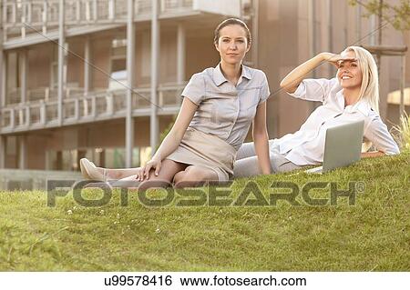 Young businesswomen with laptop on office lawn View Large Photo Image Stock Photograph - Young businesswomen with laptop on office lawn. Fotosearch