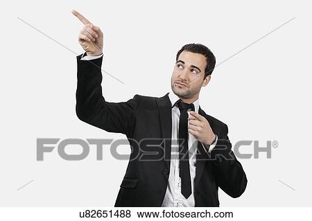 Stock Photo - Young Caucasian businessman pointing upwards against white background. Fotosearch