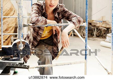 Picture - Young construction builder Woman Behind Scaffolding. Fotosearch