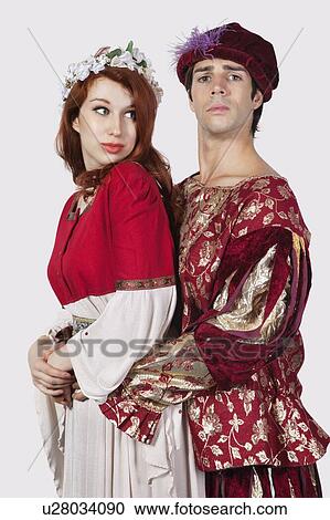 Stock Image - Young couple in periodic costumes against gray background. Fotosearch