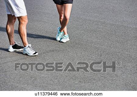 Stock Photograph - Young couple standing while talking after exercising. Fotosearch