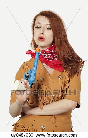Young cowgirl with toy pistol against gray background View Large Photo Image Stock Image - Young cowgirl with toy pistol against gray background. Fotosearch