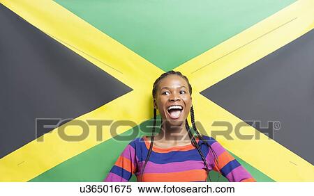 Stock Photography - Young excited woman against Jamaican flag. Fotosearch