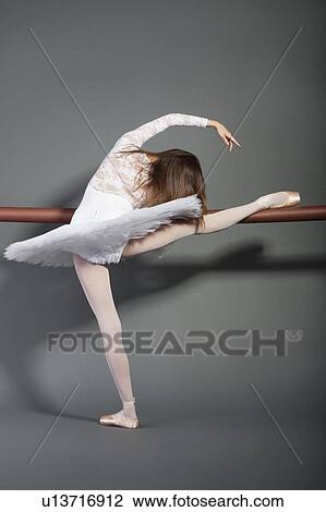Young female ballet dancer stretching at ballet bar over grey background View Large Photo Image Stock Image - Young female ballet dancer stretching at ballet bar over grey background. Fotosearch