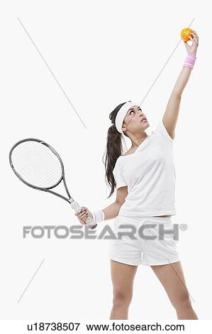 Stock Photo - Young female tennis player holding orange and racket against white background. Fotosearch