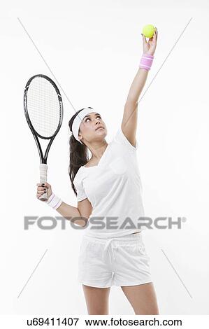 Young female tennis player preparing to serve ball against white background View Large Photo Image Stock Photo - Young female tennis player preparing to serve ball against white background. Fotosearch