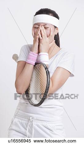 Stock Photography - Young female tennis player with hands on face against white background. Fotosearch