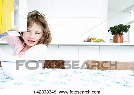 Young girl pouring cereal from box at breakfast table View Large Photo Image Stock Photography - Young girl pouring cereal from box at breakfast table. Fotosearch