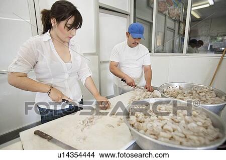 Picture - Young male and female fishmongers cutting prawns. Fotosearch