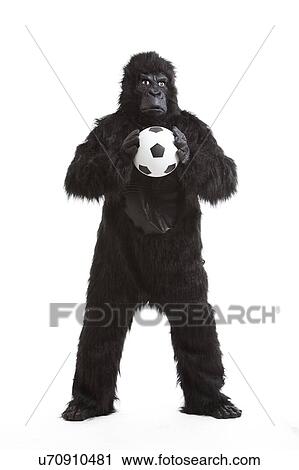 Stock Image - Young man in gorilla costume holding soccer ball against white background. Fotosearch