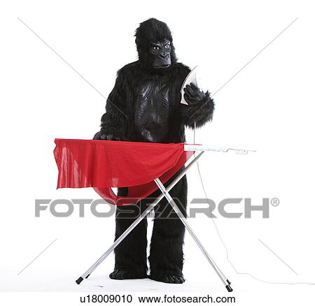 Stock Image - Young man in gorilla costume ironing red cloth against white background. Fotosearch