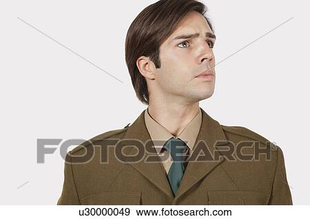 Stock Photo - Young man in military uniform looking away against gray background. Fotosearch