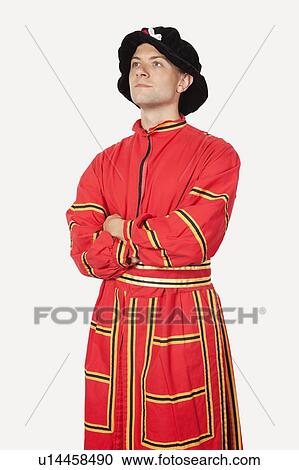 Young man in orange costume with arms crossed against gray background View Large Photo Image Stock Image - Young man in orange costume with arms crossed against gray background. Fotosearch