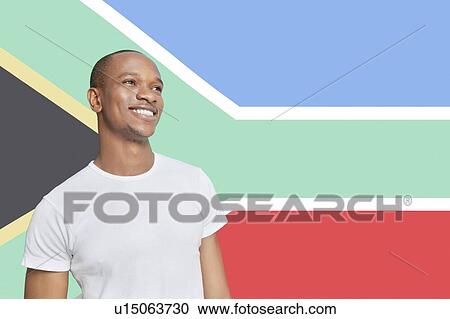 Stock Image - Young man in white t-shirt day dreaming against South African flag. Fotosearch