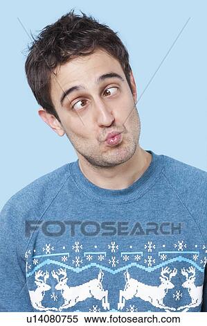 Young man making funny faces over blue background View Large Photo Image Stock Photography - Young man making funny faces over blue background. Fotosearch