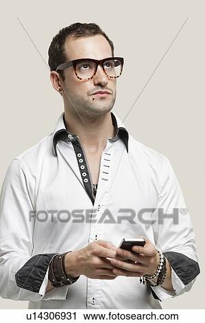 Young man using cell phone for text messaging against gray background View Large Photo Image Stock Image - Young man using cell phone for text messaging against gray background. Fotosearch