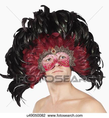 Young man wearing feathered eye mask against white background View Large Photo Image Stock Image - Young man wearing feathered eye mask against white background. Fotosearch