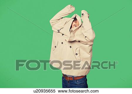 Stock Photography - Young man wearing jacket while looking from jacket over green background. Fotosearch