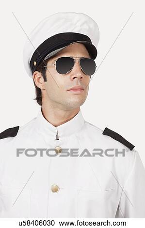 Stock Image - Young navy officer wearing glasses against gray background. Fotosearch