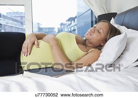 Young pregnant woman sleeping on bed at home View Large Photo Image Stock Image - Young pregnant woman sleeping on bed at home. Fotosearch