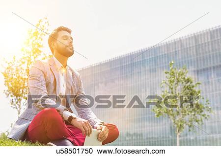 Young thoughtful businessman sitting on the grass while holding digital tablet View Large Photo Image Stock Image - Young thoughtful businessman sitting on the grass while holding digital tablet. Fotosearch