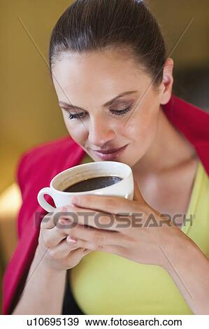 Stock Photo - Young woman holding coffee cup. Fotosearch
