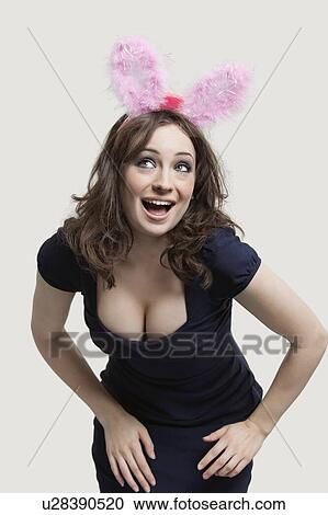 Stock Image - Young woman in playboy bunny costume against gray background. Fotosearch