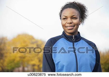 Stock Photography - Young woman in sports jacket looking away at park. Fotosearch