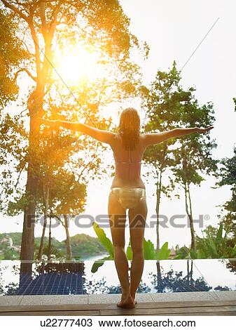 Stock Image - Young Woman in Swimming Pool at sunset. Fotosearch